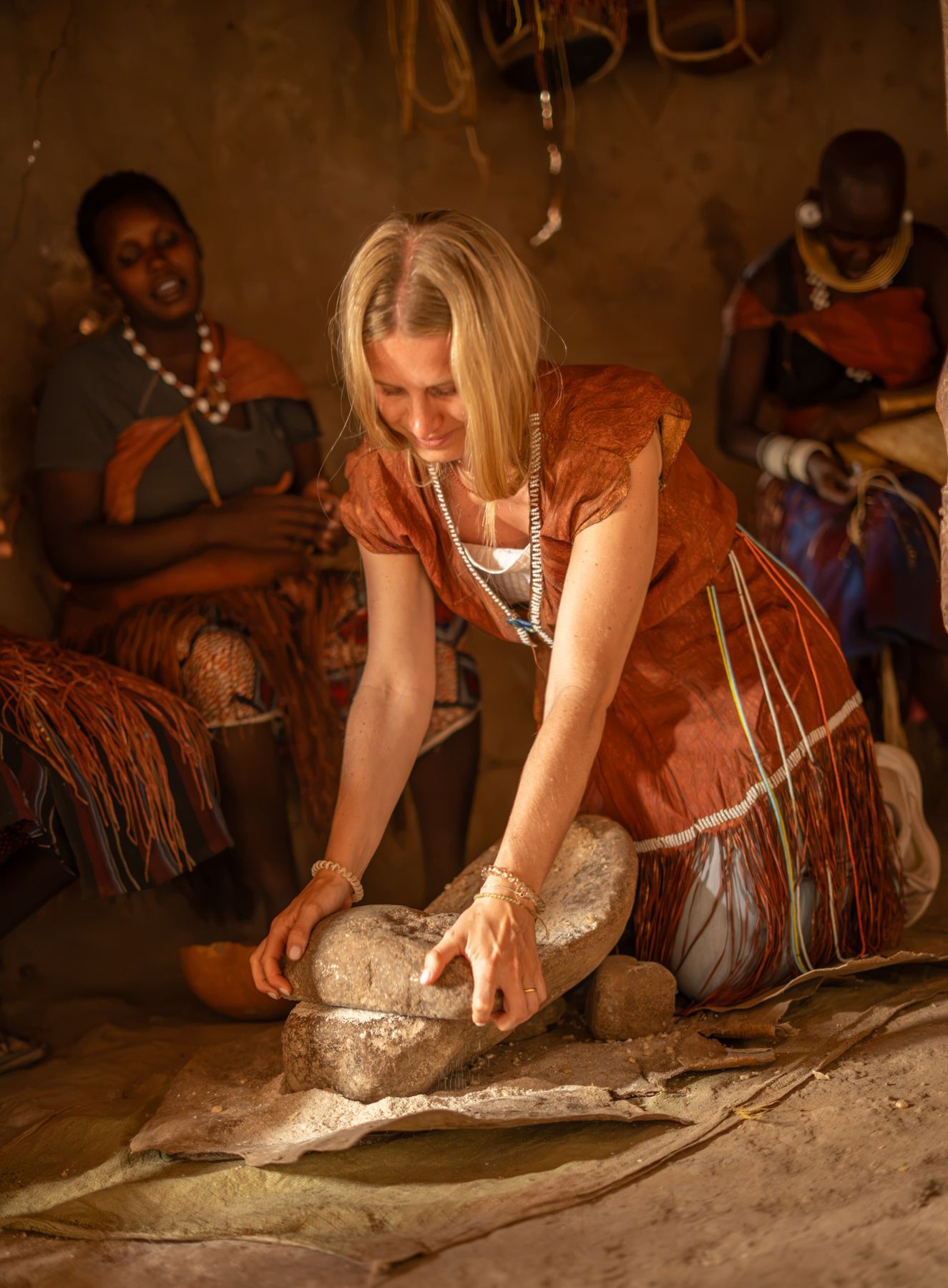 Traveller grinding grain with Datoga women near Lake Eyasi