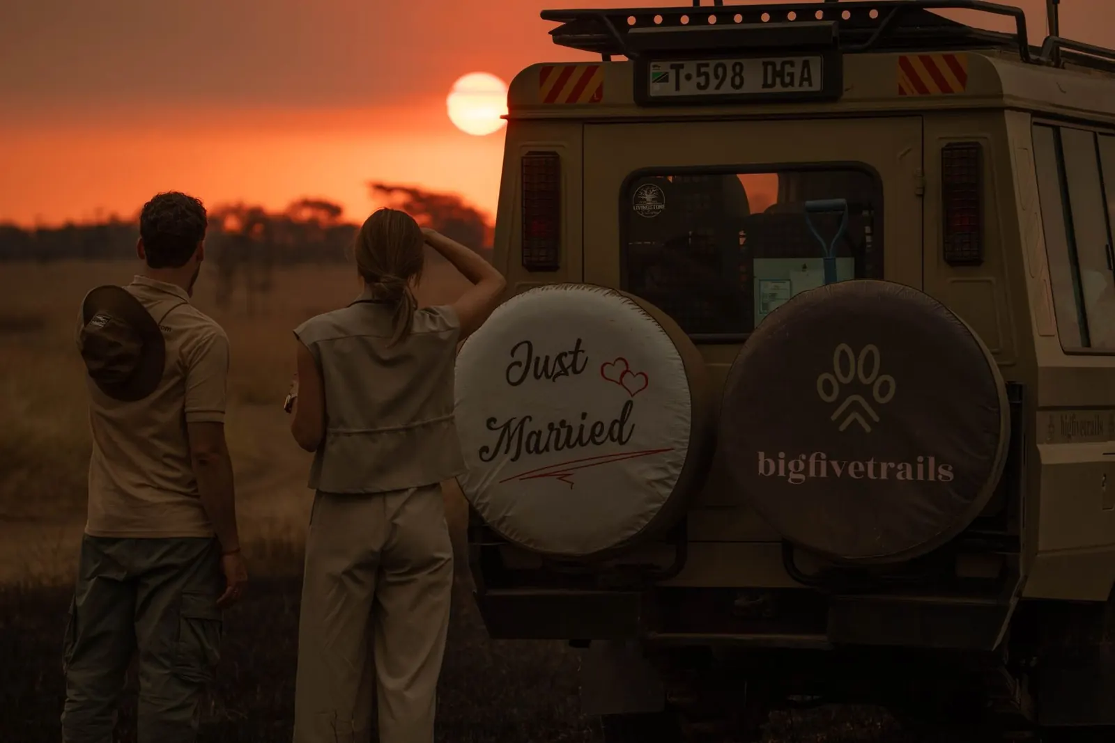 Pareja de recién casados viendo el atardecer junto a un Land Cruiser de BigFiveTrails