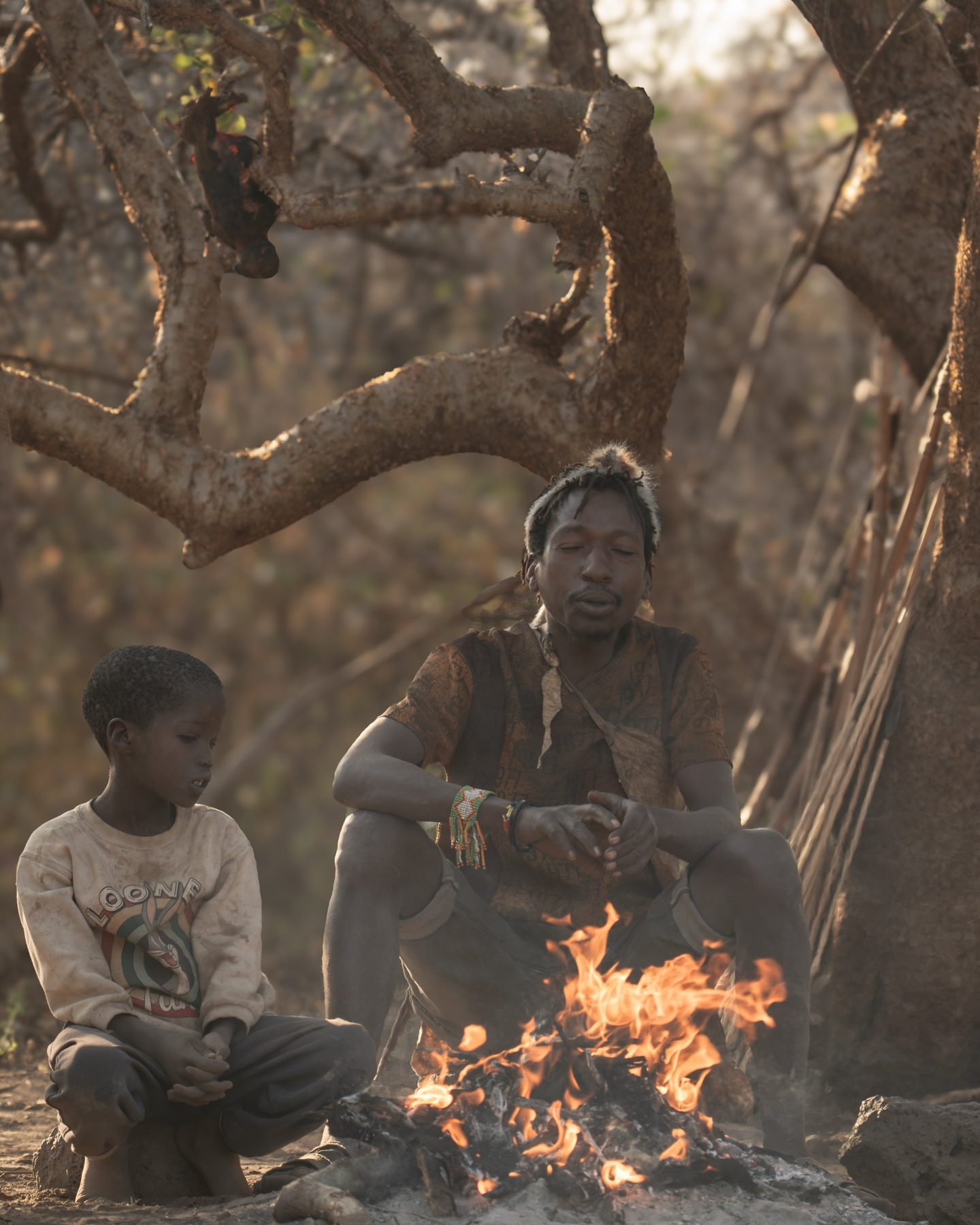 Hadzabe man and boy beside a fire at Lake Eyasi