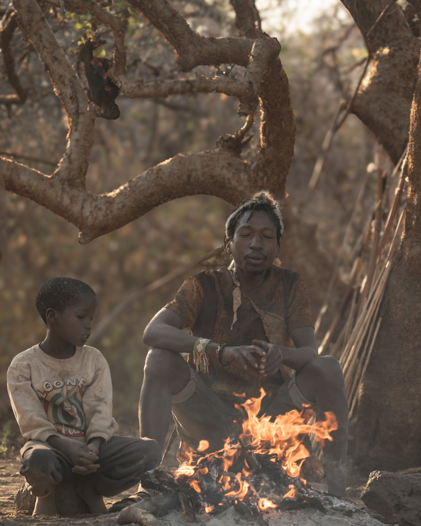 Hadzabe man and boy beside a fire at Lake Eyasi