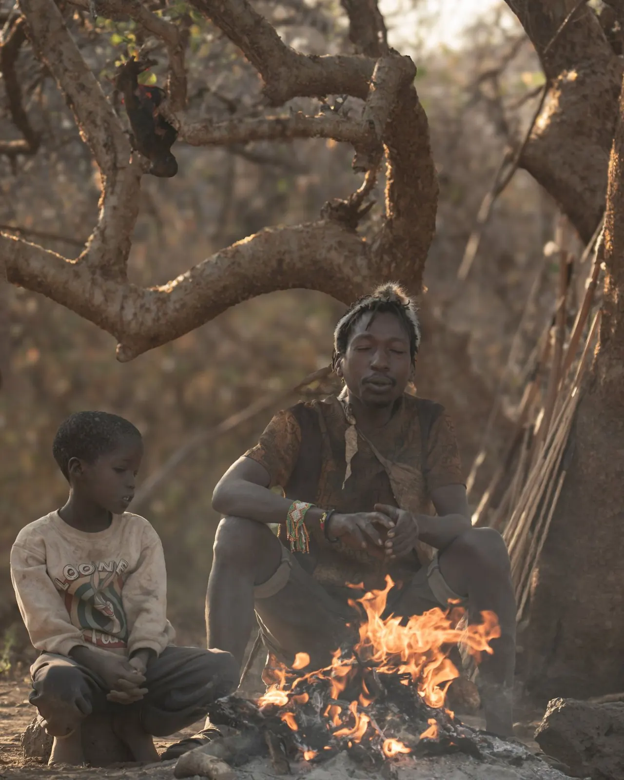 Hombre y niño hadzabe junto al fuego en el lago Eyasi