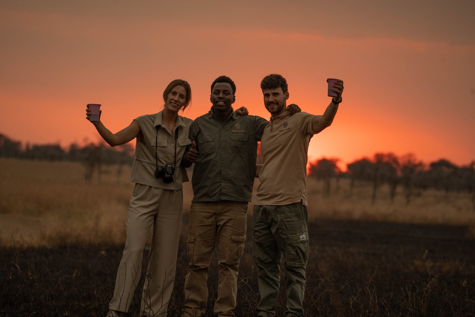 Guía de BigFiveTrails y viajeros brindando al atardecer en el Serengeti