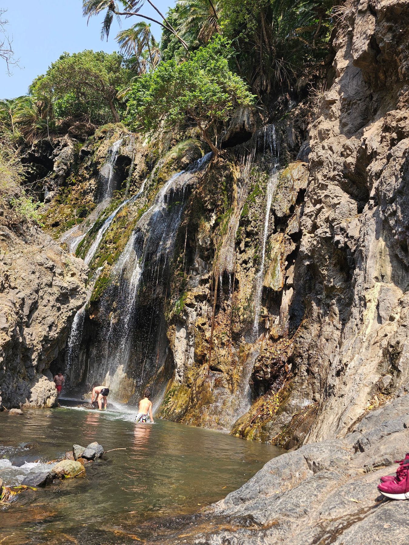 Travellers swimming at the waterfall near Lake Natron
